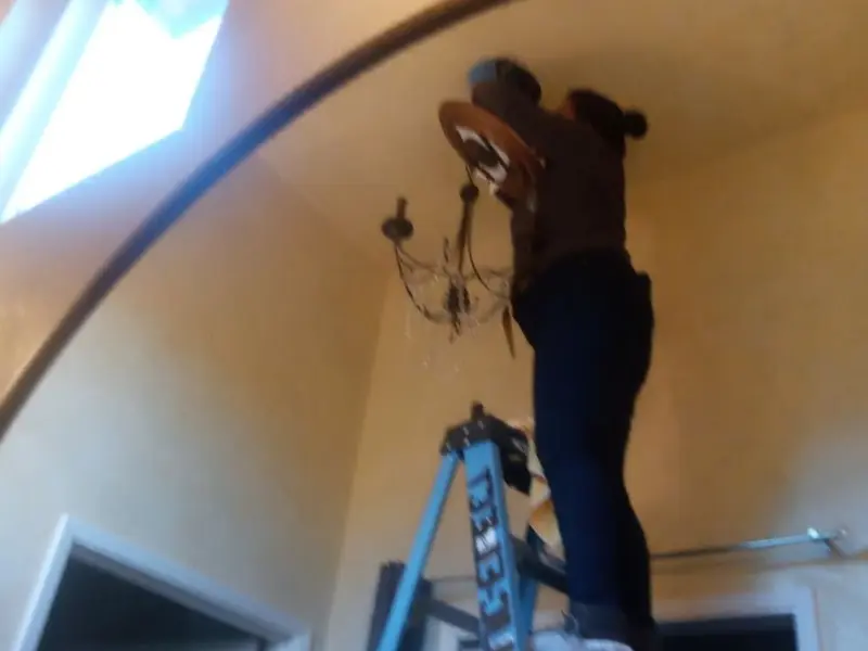 Electrician installing a chandelier in a Doolittle residence